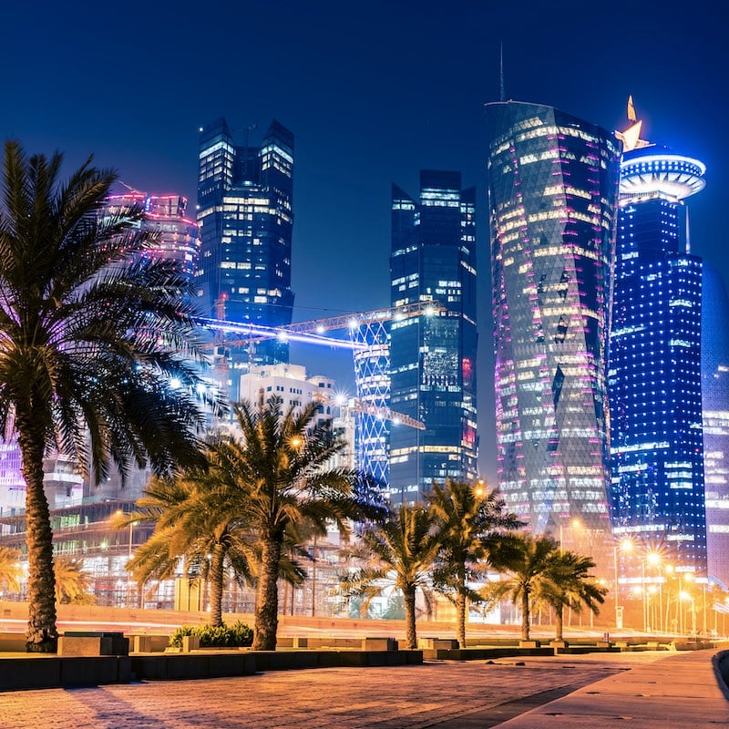 Night view on the centre of the city Doha, Qatar with many modern luxury building and skyscrapers illuminated with lots of lights.