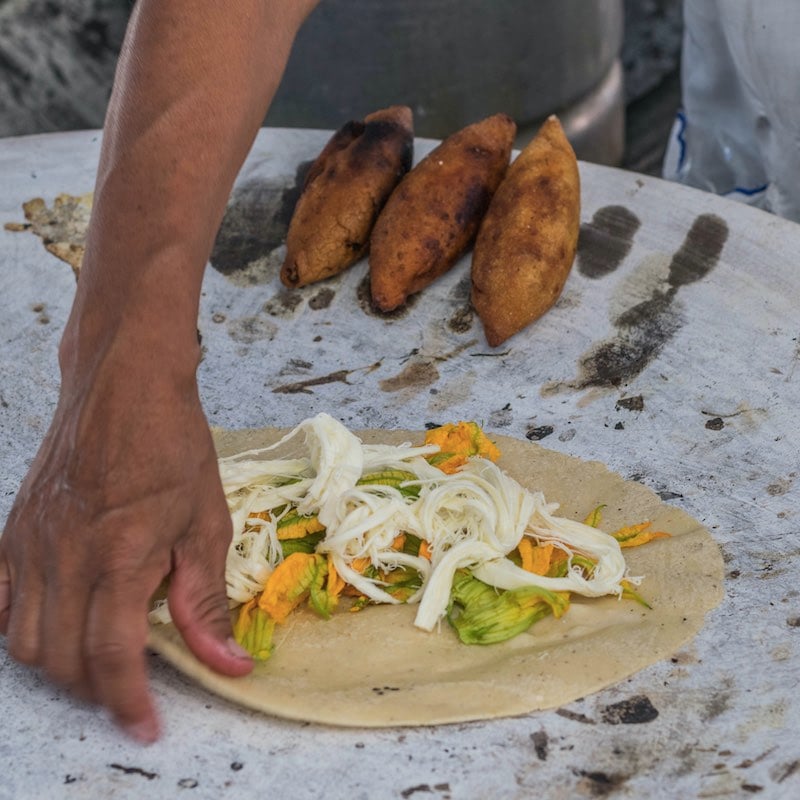 Oaxaca, Mexico- July 18, 2018: a Mexican woman preparing a squash blossom quesadilla on a large comal
