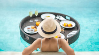A woman eating a luxury breakfast in a pool
