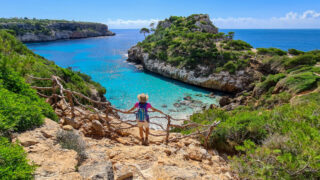 Woman standing on a cliff above the beach, Mallorca