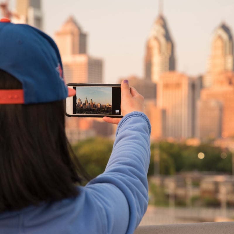 tourist taking photos of philadelphia skyline on smartphone