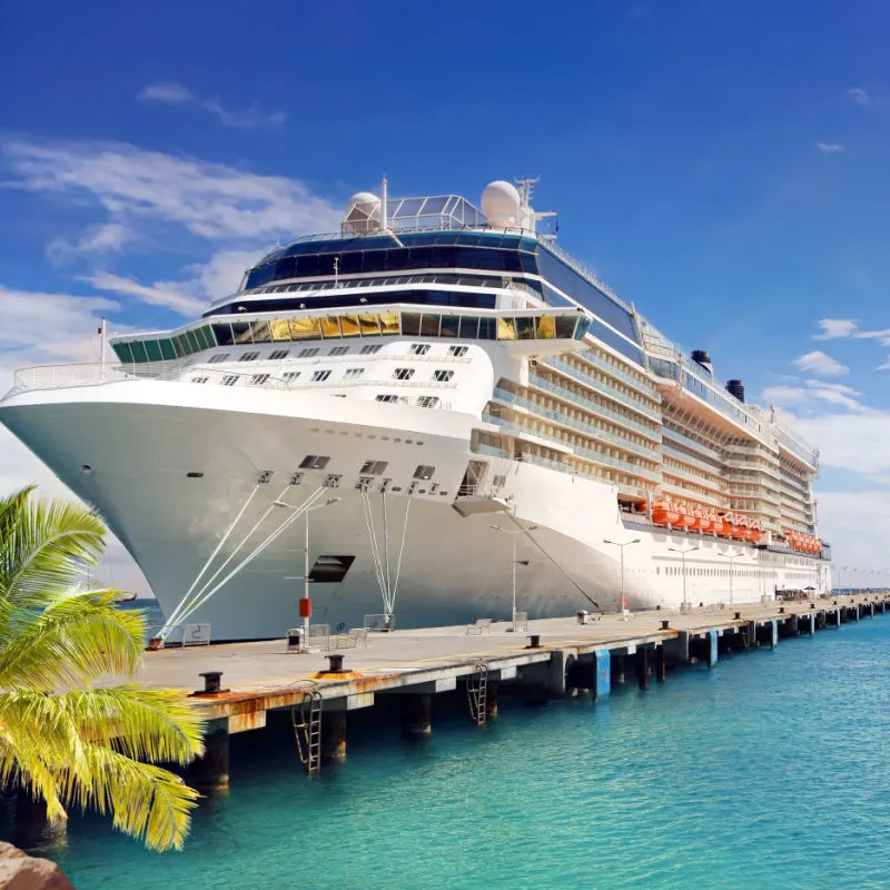a larger white cruise ship waits for passengers on a long wooden pier