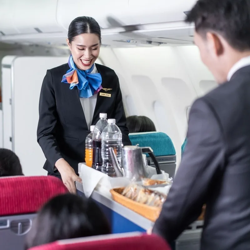 Flight Attendants Pushing A Food Trolley Across A Plane As They Serve Passengers