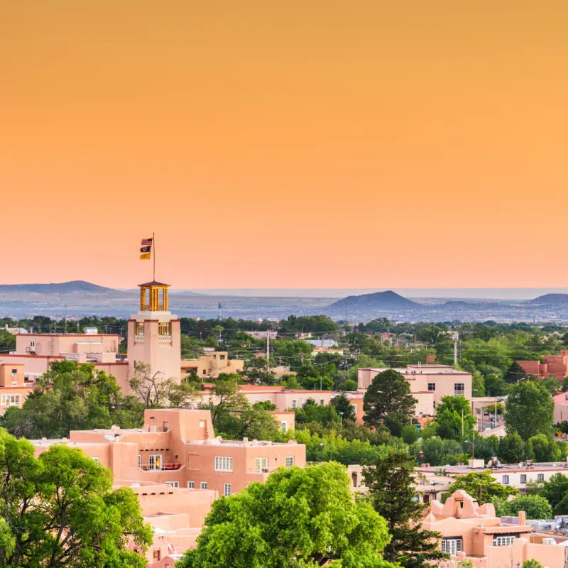 skyline of santa fe in new mexico under an orange sky at dusk
