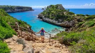 Woman standing on a cliff above the beach, Mallorca